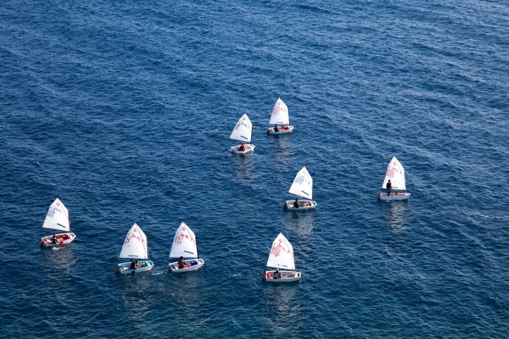 Several dinghies sailing across still blue water