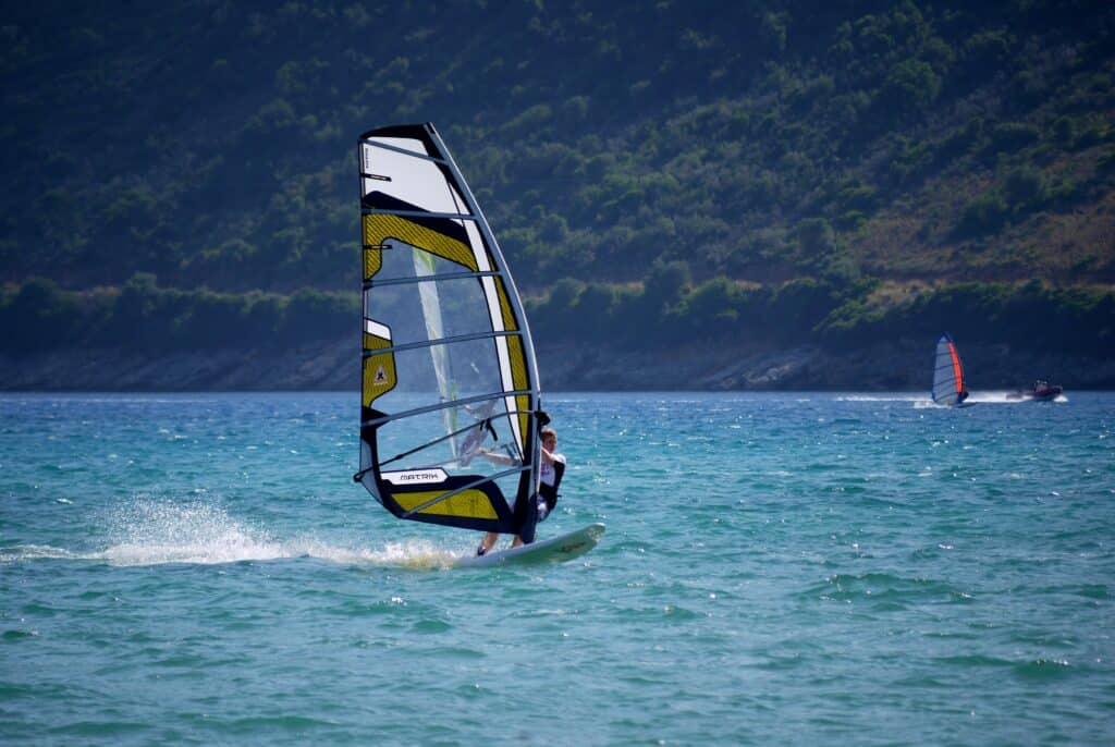 A person windsurfing with mountains in the background